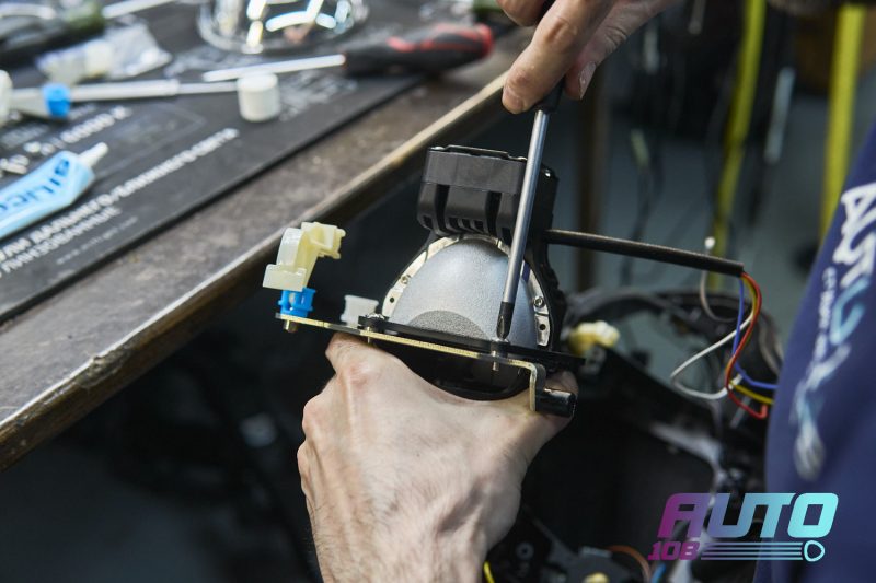 Мастер устанавливает Bi-LED линзу в штатный подвес фары BMW E90