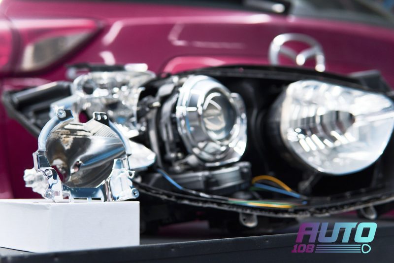 Разобранный штатный подвес Koito фары Mazda CX-5 KE рядом с ксеноновой линзой