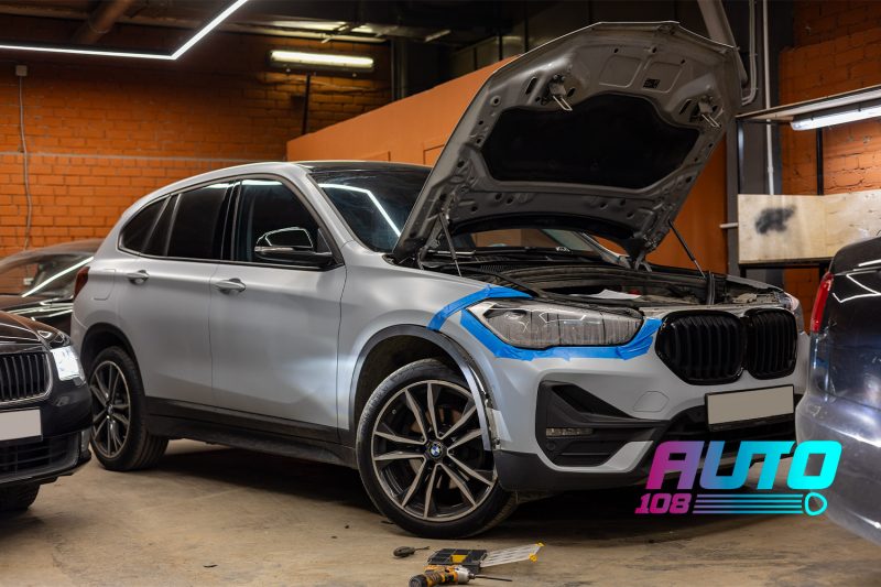 BMW X1 F48 в студии с открытым капотом, правая фара обклеена малярным скотчем перед снятием